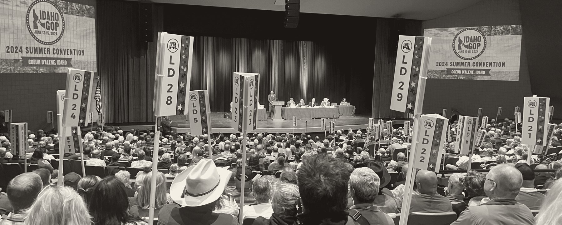 Delegates seated beneath legislative district banners at the Idaho GOP 2024 Summer Convention in Coeur d'Alene
